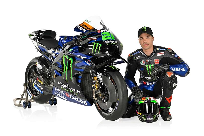 Franco Morbidelli kneels next to his 2023 Monster Energy Yamaha MotoGP bike