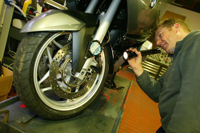 Checking a motorcycle's front wheel with a torch