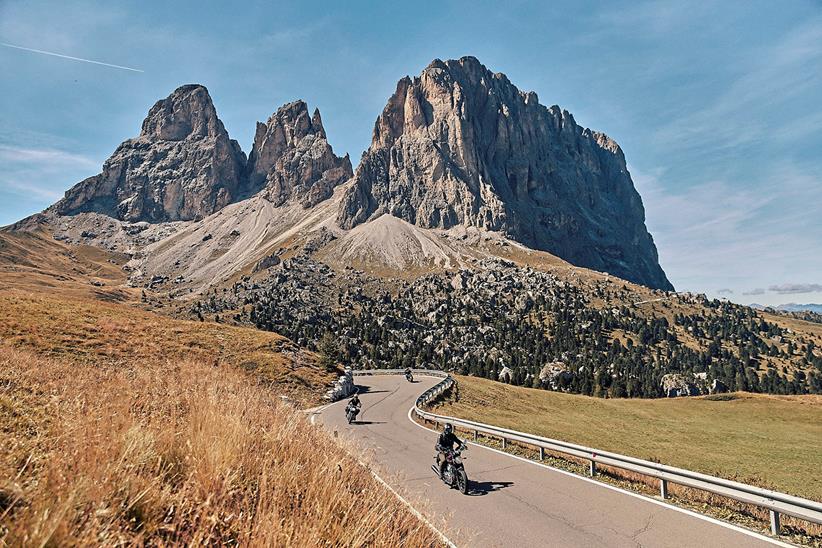 Riders travel along a winding road surrounded by mountains