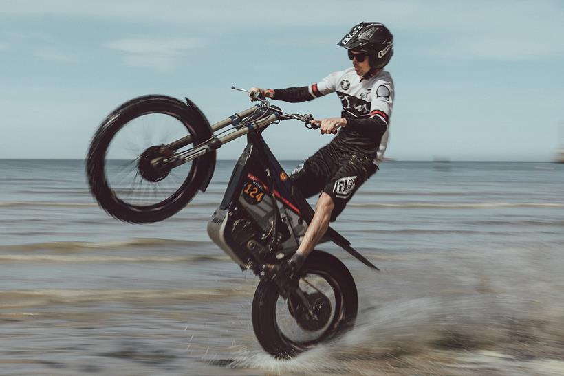 Electric dirt bike doing a wheelie on a beach