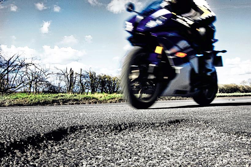 Motorbike rides past pothole