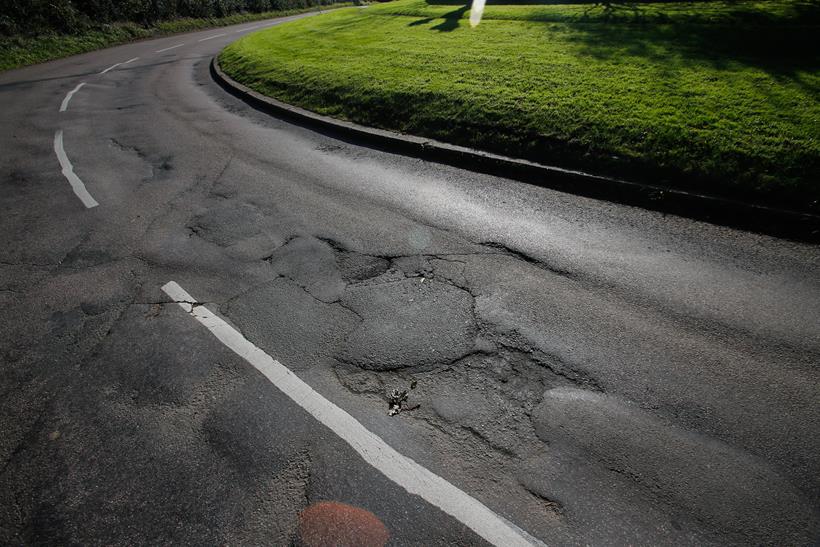 Poor UK road surface with cracks and potholes