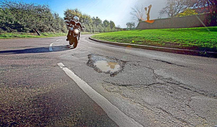 Motorcycle riding towards pothole