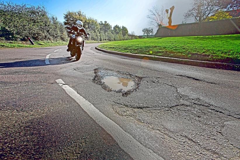 Motorcycle riding towards pothole