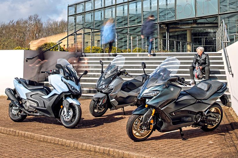 Three 2023 maxi scooters parked up outside some offices