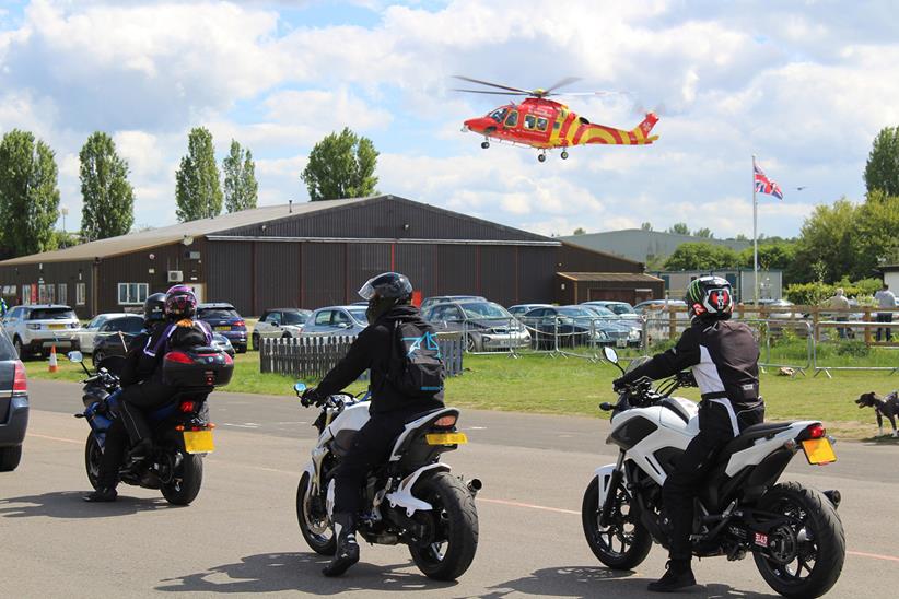 Bikers in procession with a helicopter air ambulance behind