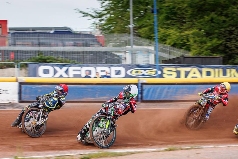 Speedway riders slide into a corner