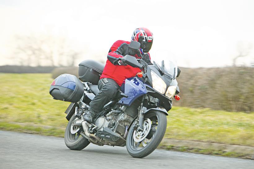 A motorcyclist riding a Suzuki Vstrom with hard luggage