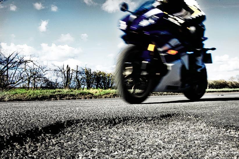 Motorcyclist avoids pothole in road