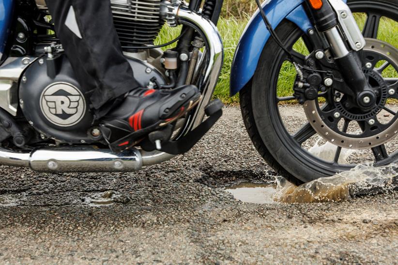 Motorcycle wheel crashing through pothole