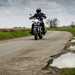 Motorcyclist rides alongside pothole littered road