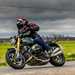 BMW R12 nineT riding past on road with dark sky backdrop