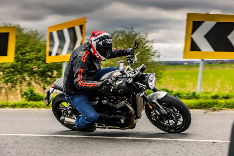 Triumph Twin 1200 riding through a left hand bend with bike and rider leaning into the corner