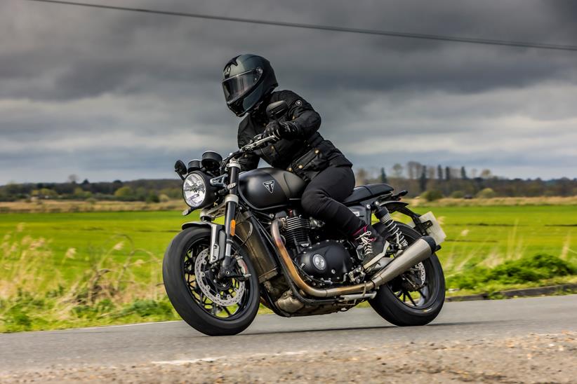 Triumph Speed Twin 1200 riding past with a dark sky backdrop