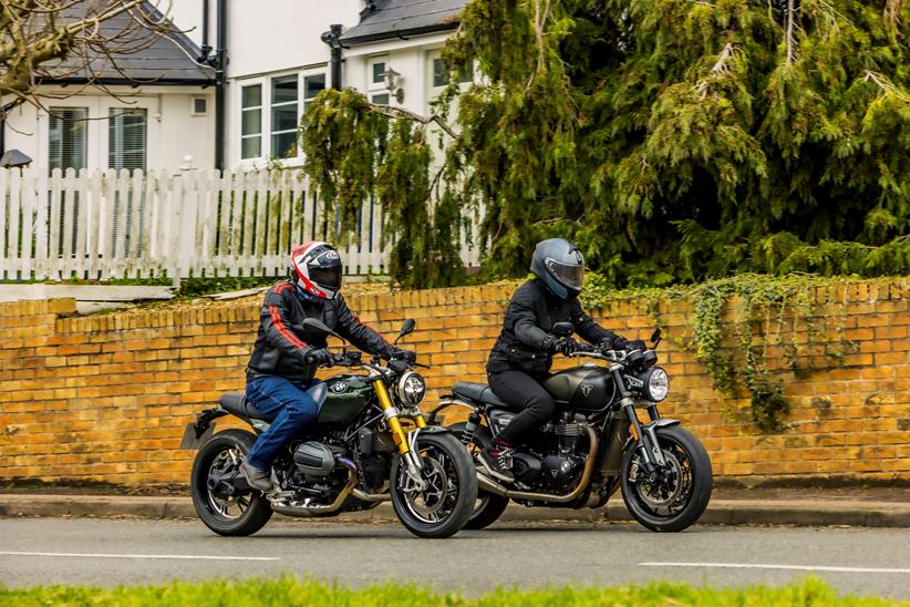 BMW R12 nineT and Triumph Twin riding past in a village scene with a brick wall back drop