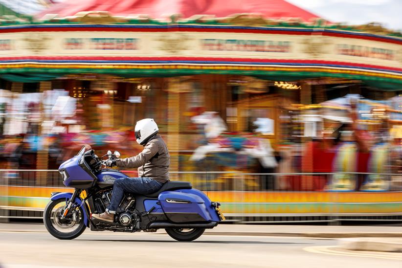 Indian Challenger Dark Horse vs Harley-Davidson Road Glide - side shot of Indian riding past in front of carousel