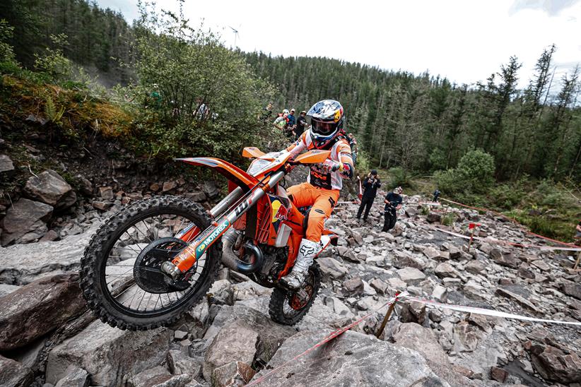 An enduro racer scrambles up a rock strewn climb