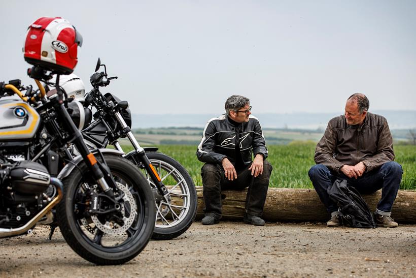 The 2024 BMW R12 and 2024 Harley-Davdison Nightster Special parked slightly off shot with riders sat next to them