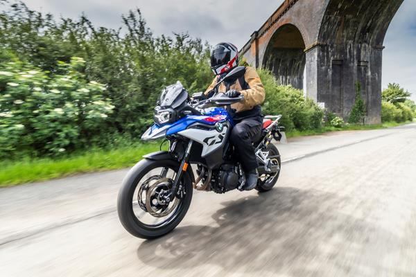 2024 BMW F800GS being ridden on a country road underneath a bridge