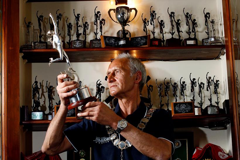 Dave Madsen-Mygdal stands with many of his Isle of Man TT trophies