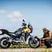 A static image of the 2024 Moto Guzzi Stelvio with the rider crouched by inspecting it