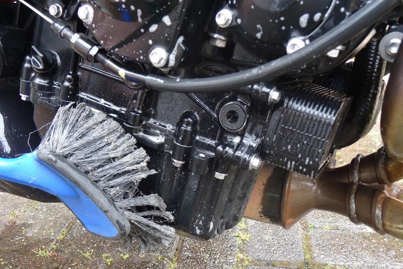 Using a scrubbing brush to clean a motorcycle