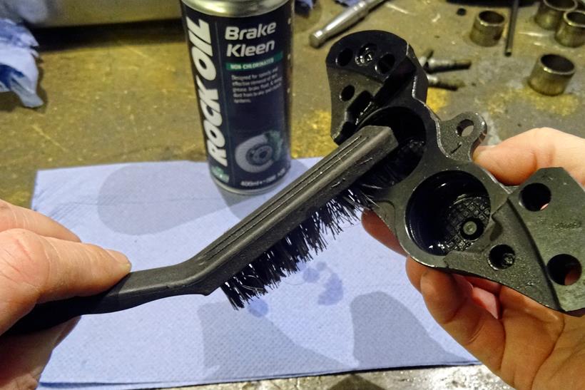 Using a brush to clean up brake caliper bores