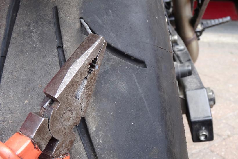 Removing a nail from a motorcycle tyre with pliers