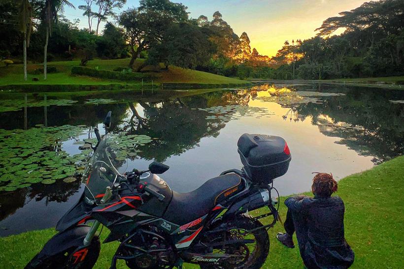 Udoh Ebaide Joy with her motorcycle overlooking lake