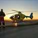 Man standing in front helicopter with sunset in the background