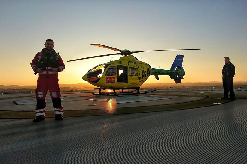 Man standing in front helicopter with sunset in the background