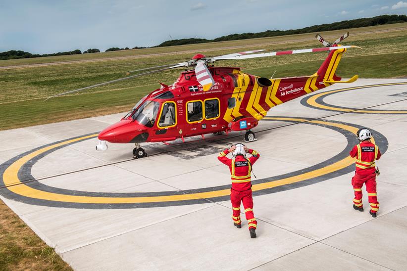 Two people walk towards Air Ambulance helicopter