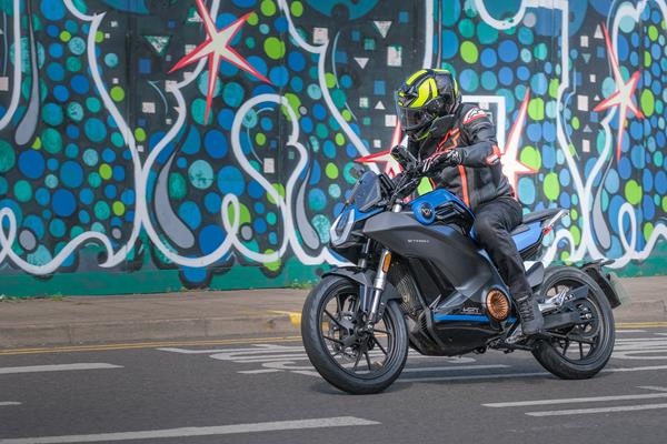 2024-on Vmoto Stash riding past a graffiti back drop