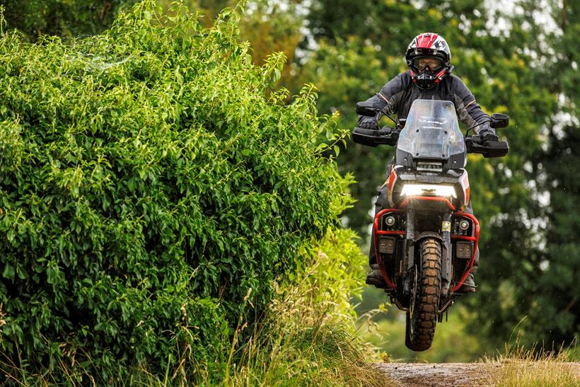 Justin Hayzelden riding a greenlane, jumping over a bridge next to a hedge