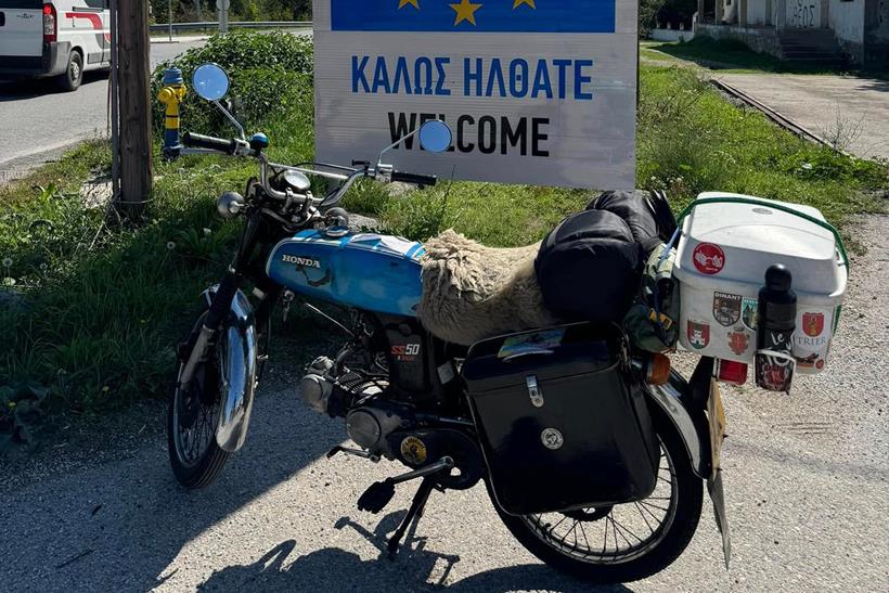 Honda SS50 near a road sign