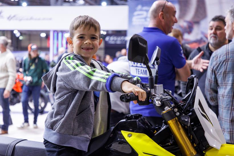 Young attendee at Motorcycle Live 2024 witting on a Suzuki DRZ-4S