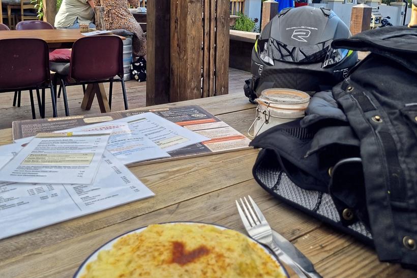 A meal sat outside with menus and motorbiking gear on the table