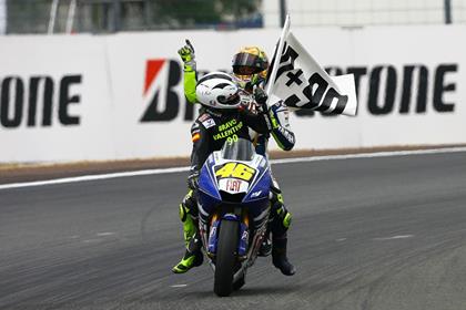 Valentino Rossi gets a lift on his own bike from Angel Nieto after he equalled his record of 90 MotoGP wins at the Le Mans race