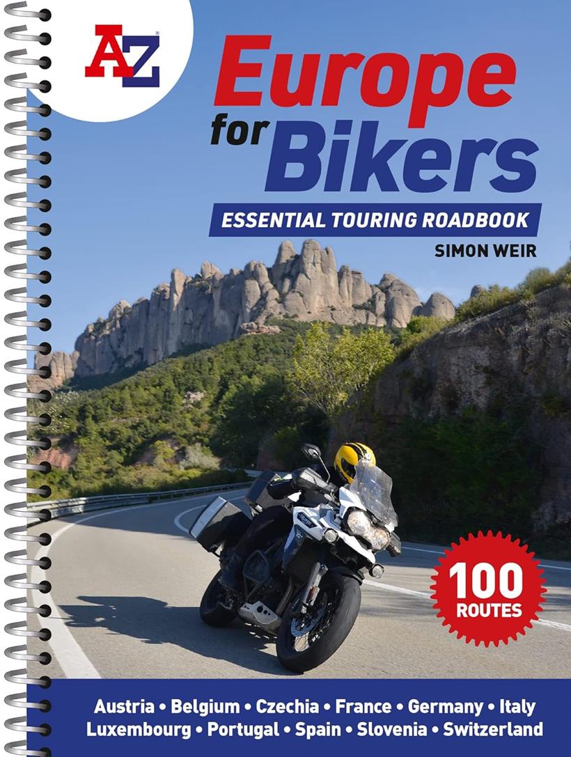 A biker taking a bend with some imposing nobbly cliff faces in the background.