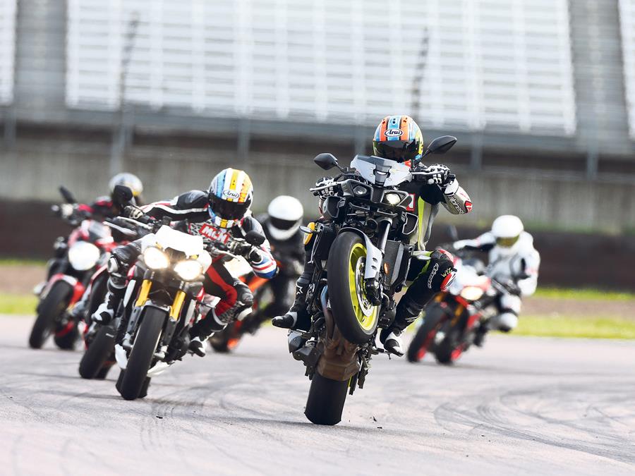 Yamaha MT-10 pulls a wheelie out of a corner with its rivals