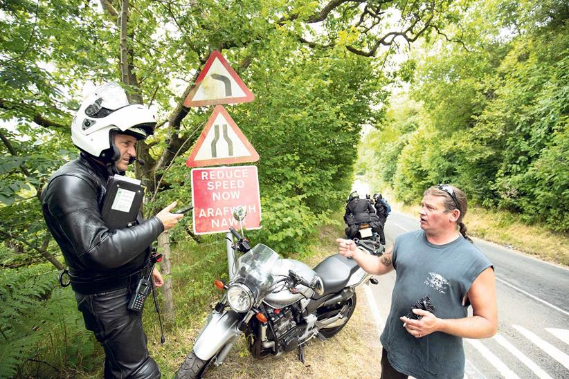 An officer speaks with a rider at the roadside