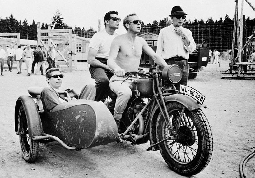 Steve McQueen riding a motorbike and sidecar