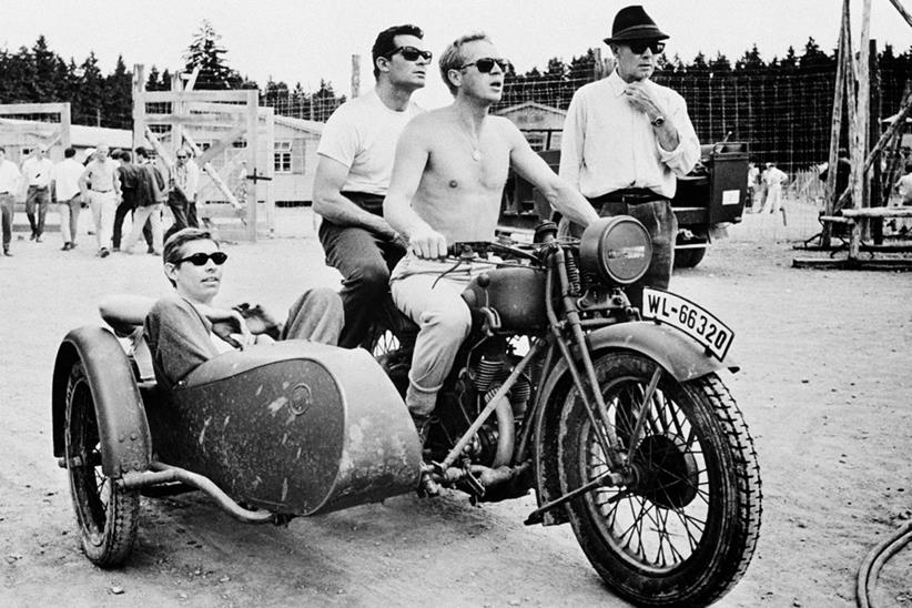 Steve McQueen riding a motorbike and sidecar