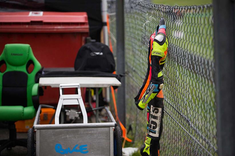 A rider hangs their leathers on the fence