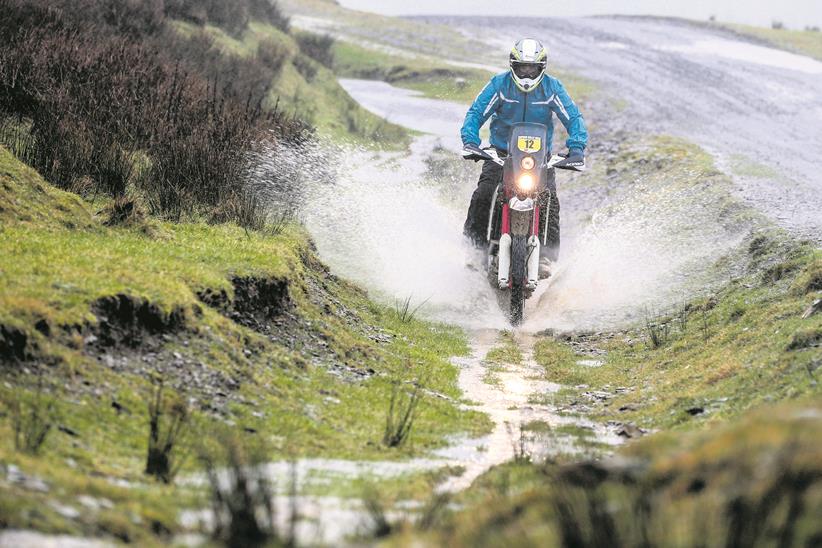 2019 AJP PR7 650 riding down a muddy puddled trail