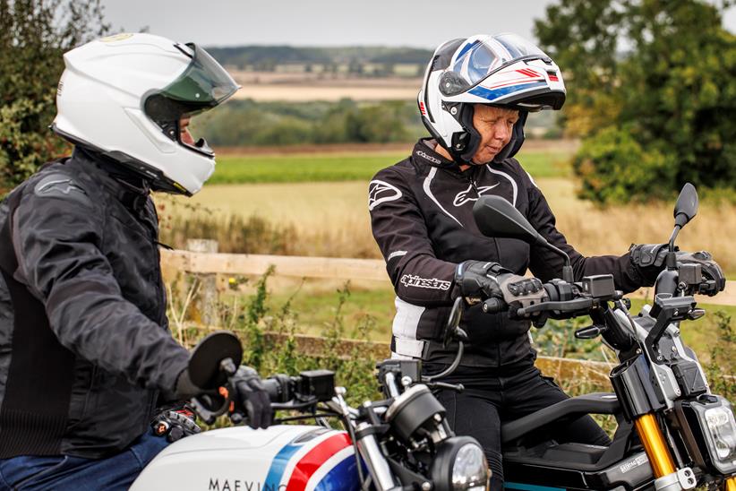 Two people stradling a pair of bikes, paused, discussing them