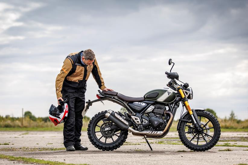 One person examining a Triumph Scrambler 400