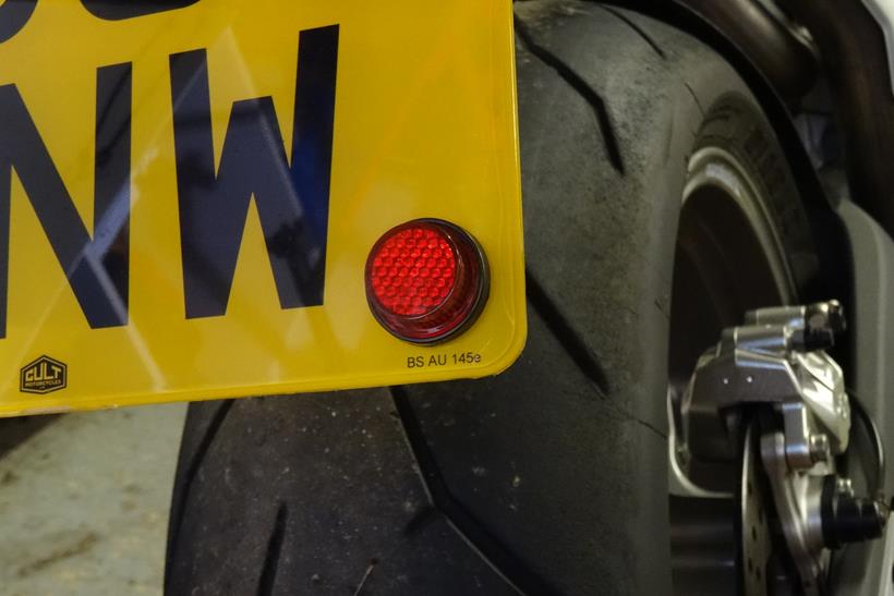 A legal motorcycle number plate featuring a reflector