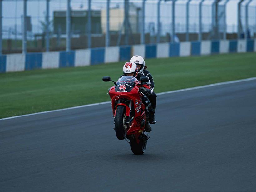 Ron Haslam wheelies with a pillion at the race school