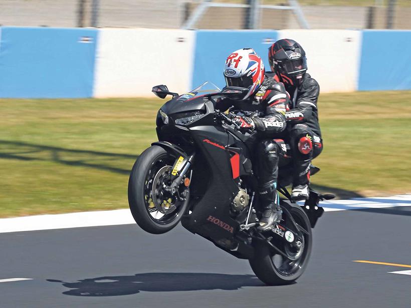 Ron Haslam pops a wheelie with a pillion 